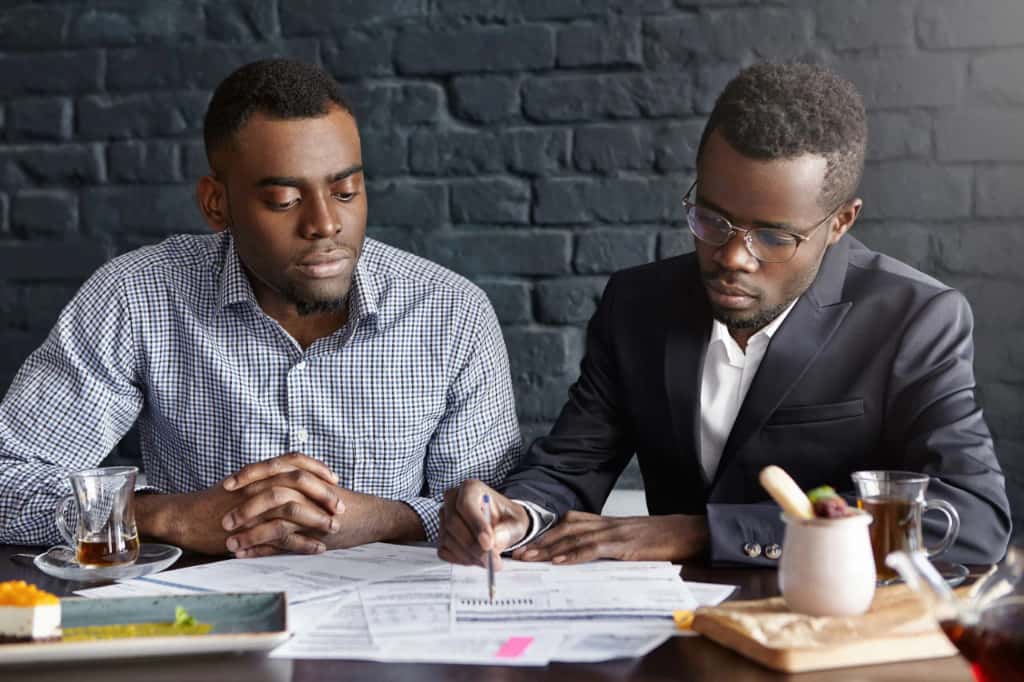 Nigerian property lawyer reviewing land purchase document with a client